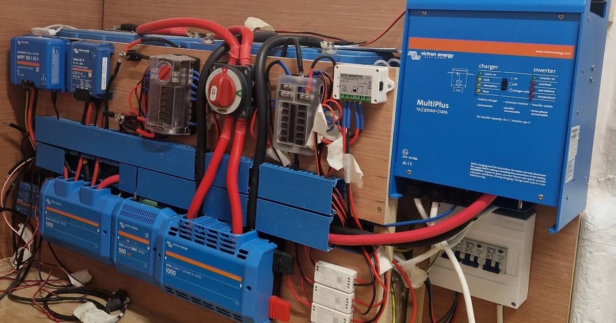 Invertor/încărcător Victron, regulatoare solare și bare de conexiune montate pe peretele unui rulote